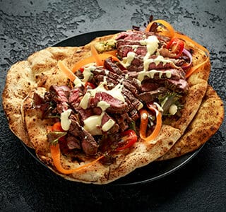 Naan bread with beef strips and a topping of extra mature cheese