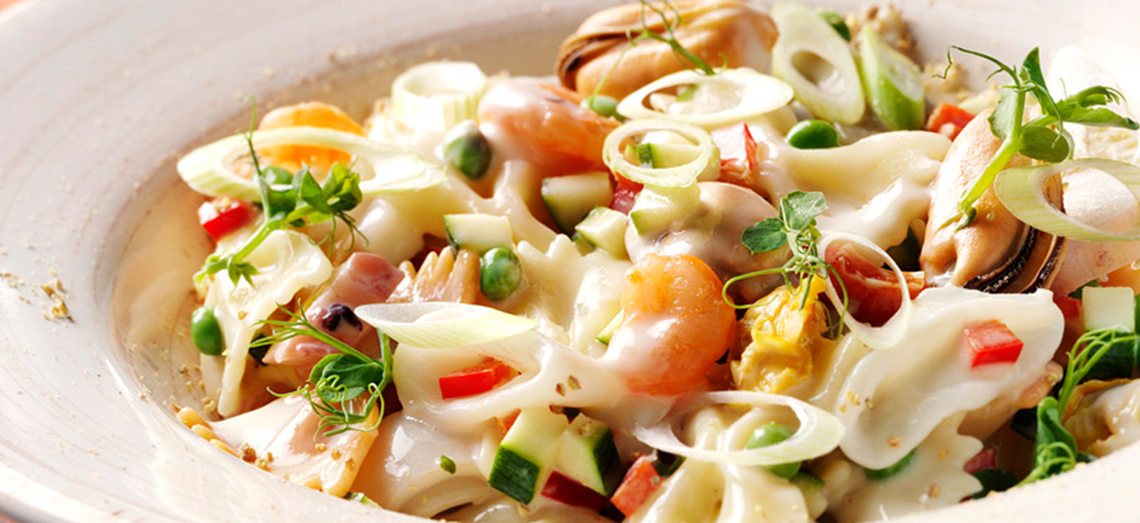 Farfalle met zeevruchten, paprika, courgette en een magere kaassaus