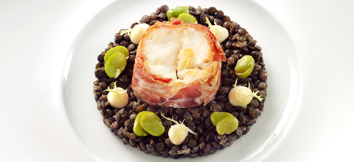 Gebakken zeewolffilet met zwarte linzen en een topping van geitenkaas